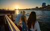 Hamburg Highlights: Drei junge Menschen stehen bei Sonnenuntergang am Hamburger Hafen und blicken in Richtung Meer