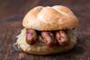 Sehenswürdigkeiten von Nürnberg für den Gaumen: Drei Nürnberger Rostbratwürste mit Sauerkraut in einer Semmel.