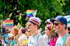 Top Queer Events Europa: Beim Christopher Street Day in Budapest sieht man mehrere Männer in der Parade, die sich mit Regenbögen im Gesicht geschminkt haben. Im Hintergrund werden Regebogen-Flaggen geschwenkt.  