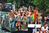 Top Pride Events Europa: Man sieht ein Boot in einer Gracht von Amsterdam mit feiernden Menschen, die in Regenbogenfarben gekleidet sind. 