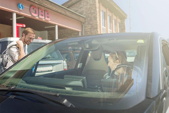 Sujet Nahallo Carsharing, Textinsert: Am Bahnhof steigt eine Person in ein Auto zu