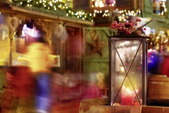 Laterne vor einer weihnachtlich dekorierten Holzhütte