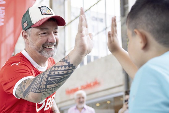 Tischfußball-Weltmeister Vladimir Drabik klatscht mit einem Jungen ein. 