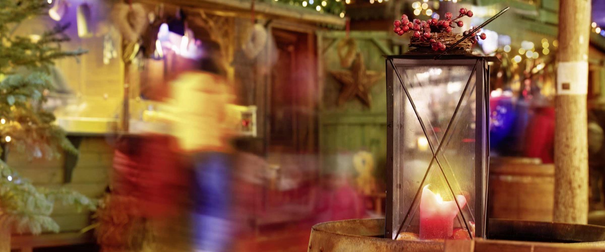 Laterne vor einer Punschhütte, die weihnachtlich dekoriert ist