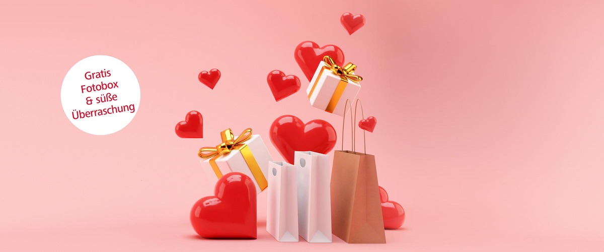 Geschenksackerl, Herzluftballons und Pakete auf rosa Hintergrund. Weißer Störer mit Text: Gratis Fotobox und süße Überraschung. 