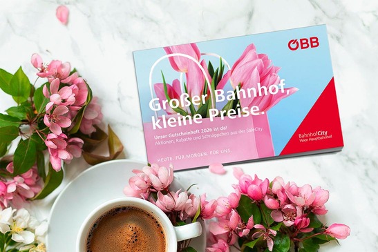 Gutscheinheft und im Hintergrund Blumen und eine Kaffeetasse