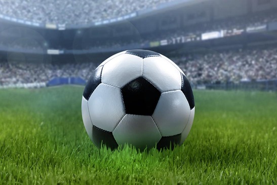 Fußball auf einer grünen Wiese in einem Fußballstadion