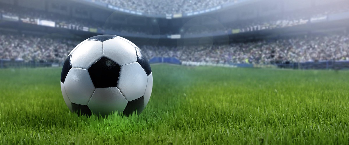 Fußball auf einer grünen Wiese in einem Fußballstadion