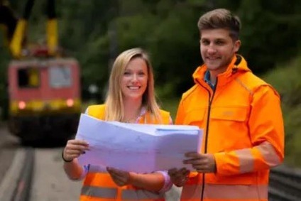 Frau und Mann im Gleisbereich beim Lesen eines Planes
