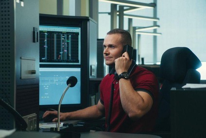 Fahrdienstleiter sitzt auf ihren Arbeitsplatz. Im Hintergrund Computerbildschirme