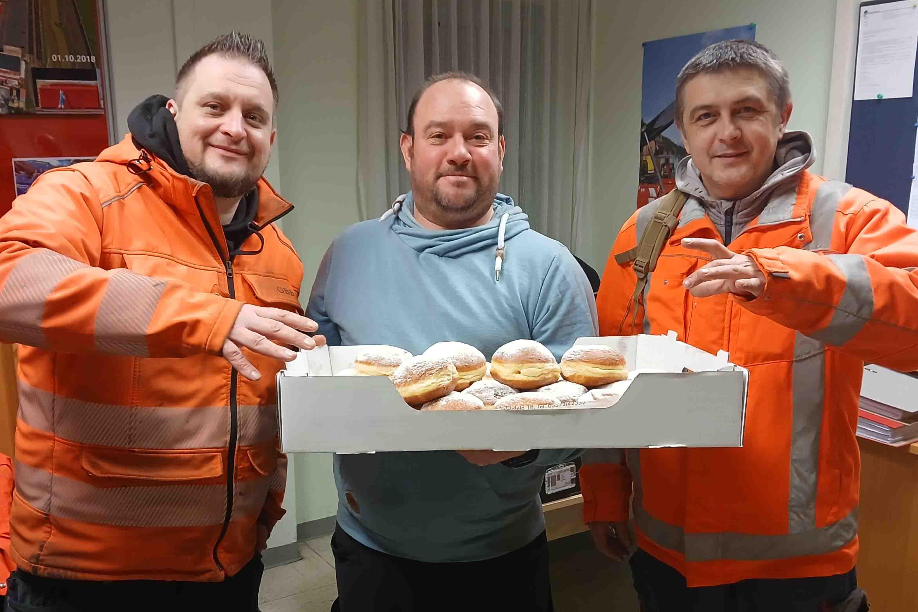 Three people holding carnival doughnuts.