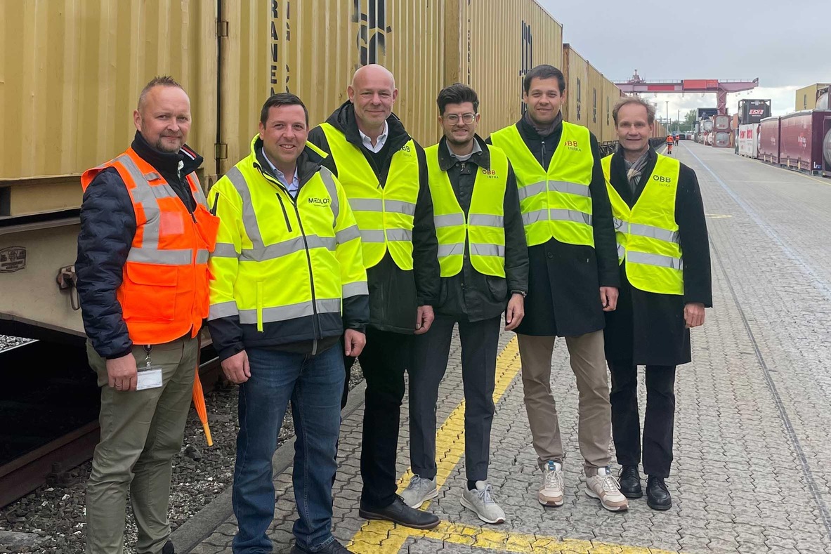 Six people next to a freight train