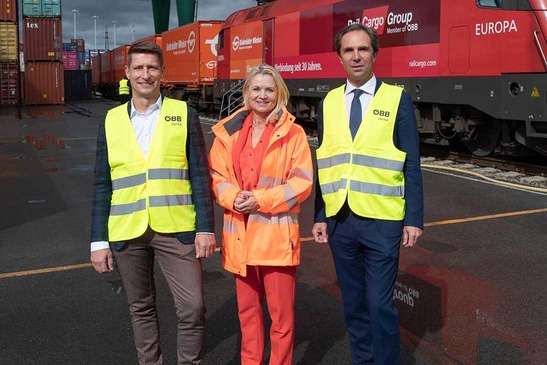 Three people in front of a freight train