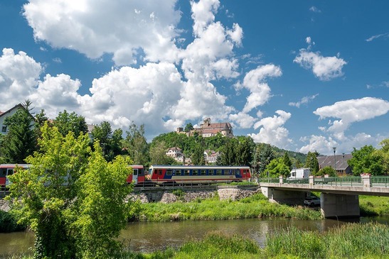 Foto Kamptalbahn<br/>Textinsert: Landschaftbild mit Zug, Brücke, Auto und Burg im Hintergrund