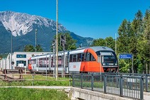 Foto Bahnhof Puchberg am Schneeberg<br/>Textinsert: Haltestelle mit Zug und Bergen im Hintergrund