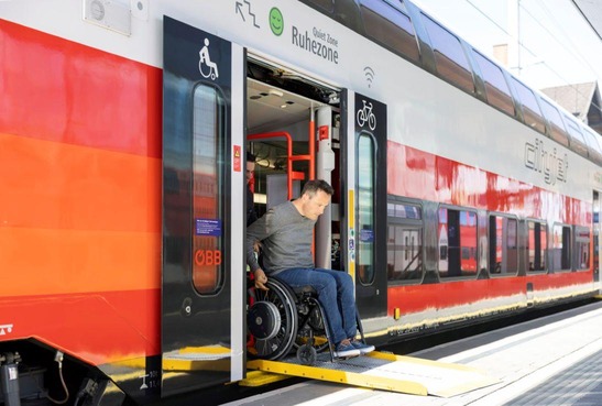 Mann fährt mit einem Rollstuhl aus dem Zug - barrierefreies Reisen