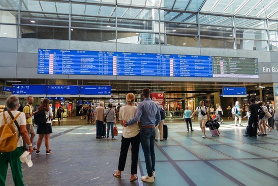 Hauptbahnhof Wien Blick auf den großen Bahnsteiganzeiger, Personen im Hintergrund