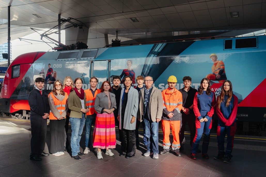Lehrlinge mit Ausbilder:innen und Vorständin Silvia Angelo am Bahnhof mit der Lehrlingslok