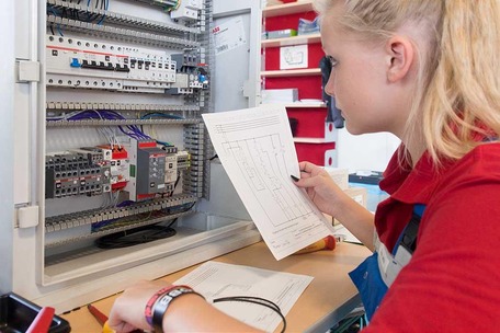 Apprentice at control cabinet with instruction
