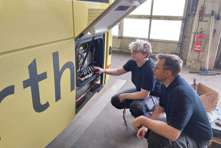 Weiblicher Lehrling und Ausbilder vor Postbus