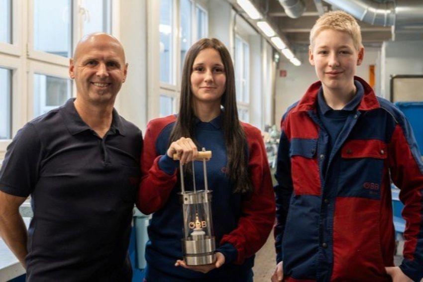 2 Lehrlinge und ein Ausbilder zeigen das selbstgemachte Friedenslicht