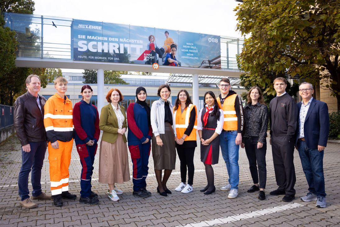 Lehrlinge stehen mit Vorständing Siliva Angelo und ihren Lehrausbildern vor der Lehrwerkstätte Wien