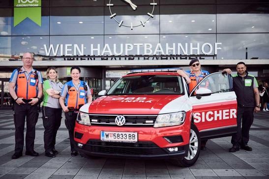 Sujet Unternehmen. Fünf Mitarbeiter:innen vor einem Sicherheits-Auto am Hauptbahnhof.