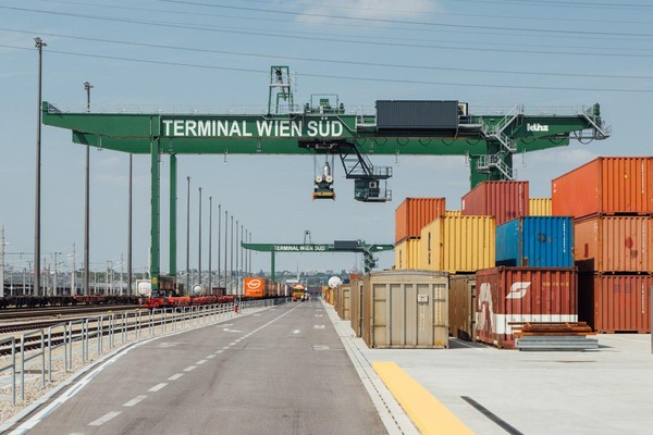 Auf diesem Foto ist ein Portalkran zu sehen. Des Weiteren stehen mehrere Container zum verladen bereit. 