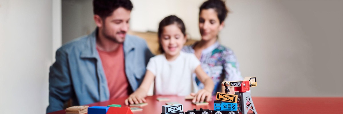 Familie, Mutter, Vater und Knd spielen am Tisch