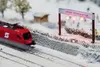 Roter ÖBB Zug auf Modellbahnstrecke in Winterlandschaft. 