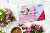 Gutscheinheft und im Hintergrund Blumen und eine Kaffeetasse
