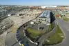 An aerial view of a large terminal area featuring a construction site, several tracks, a modern building with solar panels on the roof, and surrounding roads and industrial sites.