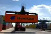 Vehicle lifts a container and stacks it with the others.