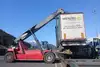 A reach stacker lifts a container onto a freight wagon.