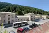 Photo of Bad Gastein train station building<br/>Text insert: Train station building with bus and parked cars