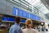 Frau und Mann schauen sich die Abfahrtsmonitore am HBF Wien an