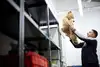 Ein Mitarbeiter des Lost and Found hebt einen großen Teddybären aus einem Regal.