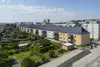 Textinsert: Foto Linz, Strachgasse, Außenansicht Wohnbau, straßenseitig, parkenden Autos und einer Kleingartensiedlung links