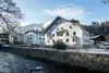 Textinsert: Foto Kitzbühel, Bahnhofstraße 11,  Außenansicht Wohnbau, straßenseitig mit Balkon und Fluß im Vordergrund