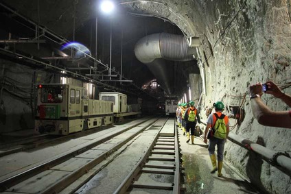 Blick in einen Tunnel mit Bauzug, mehreren Gleisen und Exkursionsteilnehmern 