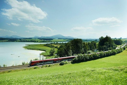 Railjet fahrend in der Landschaft. Im Hintergrund sieht man noch einen Fluss.