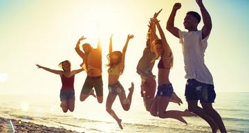 Junge Menschen springen am Sandstrand in die Luft