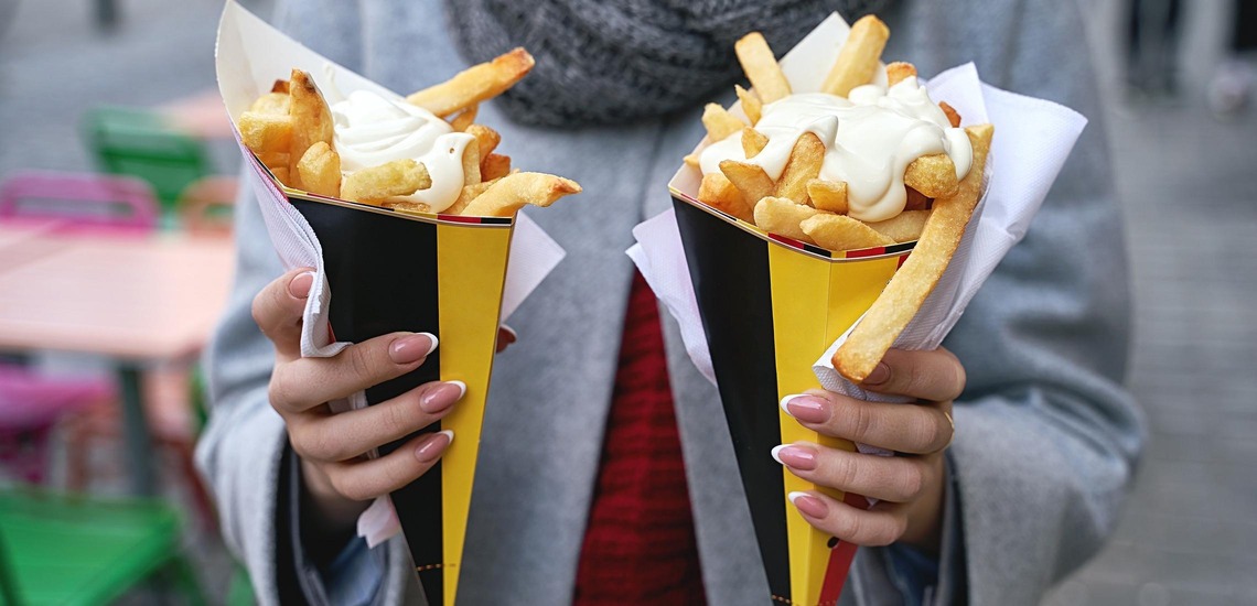 Sehenswürdigkeiten in Brüssel: Eine Frau hält zwei Portionen Pommes Frites mit Mayonnaise in der Hand.  