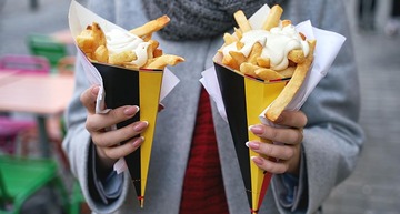 Sehenswürdigkeiten in Brüssel: Eine Frau hält zwei Portionen Pommes Frites mit Mayonnaise in der Hand.  