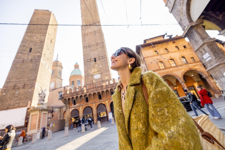 Urlaub in Italien: Eine junge Frau schlendert lachend durch die Altstadt von Bologna.