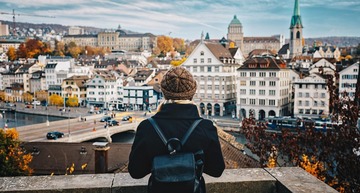 Sehenswürdigkeiten in Zürich: Eine junge Frau blickt bei herbstlichem Wetter auf die Altstadt von Zürich. 