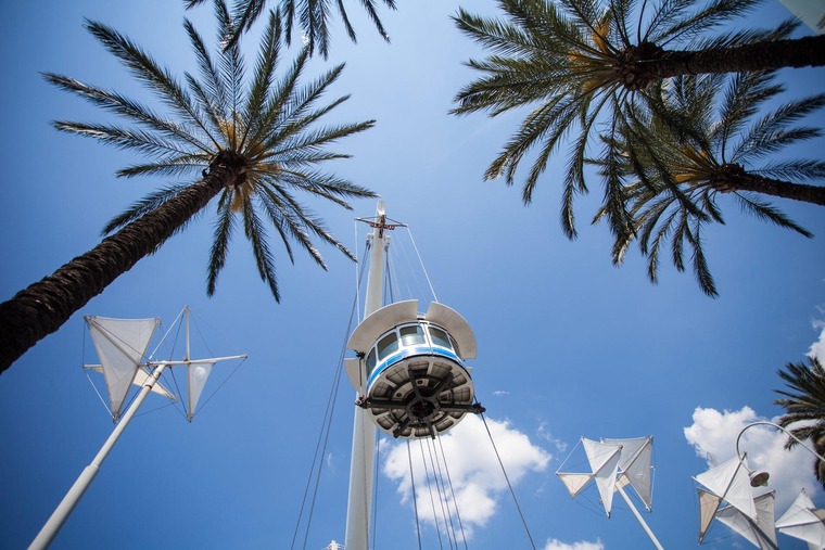Genua Sehenswürdigkeiten: Sicht auf den Aufzug „Bigo“ von unten mit blauen Himmel und Palmen in Genua