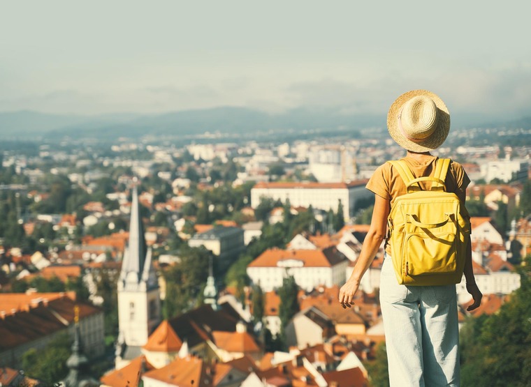 Städtetrips Europa: Eine junge Frau mit Rucksack blickt vom Schloss Ljubljana auf die Stadt hinab. 