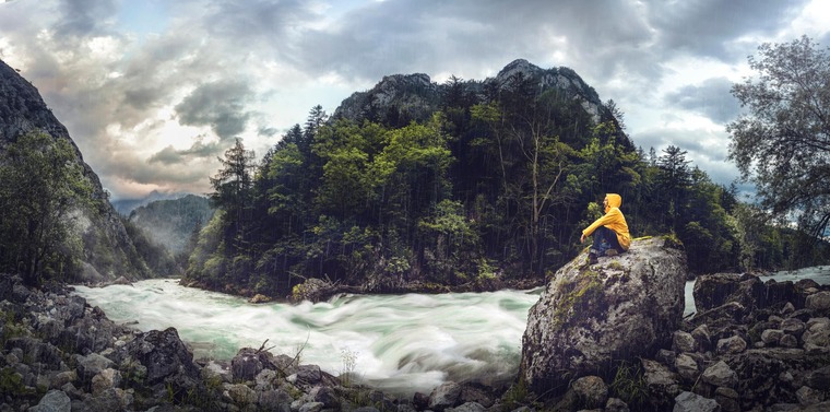 Wanderer sitzt am Fluss im Nationalpark Gesäuse