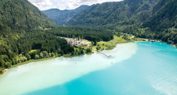Urlaub am Weissensee: Panoramaaufnahme von einem Weissensee-Strand mit türkisblauen Wasser. 